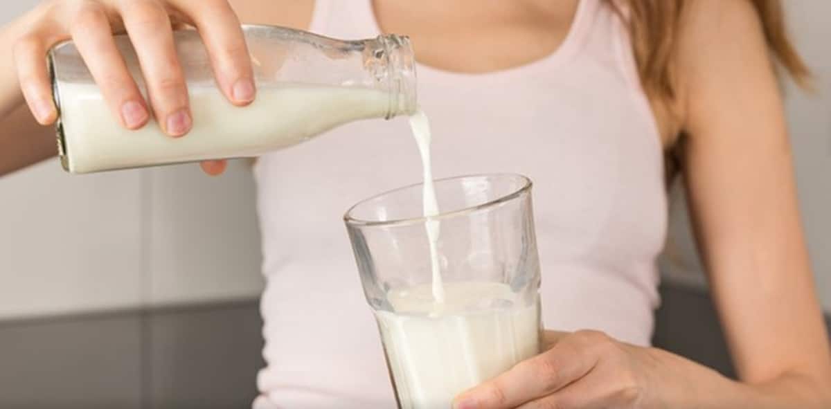 Mulher servindo o leite no copo