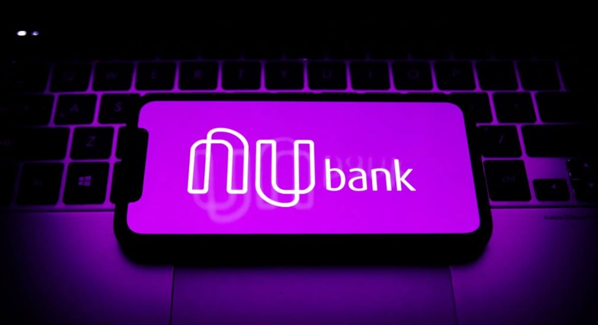 App do banco digital Nubank acessado em smartphone em cima de notebook (Foto: Reprodução/ Jakub Porzycki/ NurPhoto/ Getty Images)